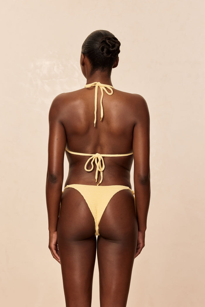 Back view of Palma Top in Honey Crinkle showing adjustable halter and back ties with gold caps on beige background