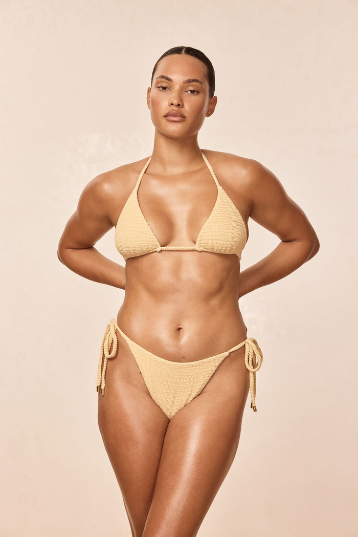 Front view of Palma Top in Raffia Crinkle showing triangle cups and halter tie straps on model with beige studio background