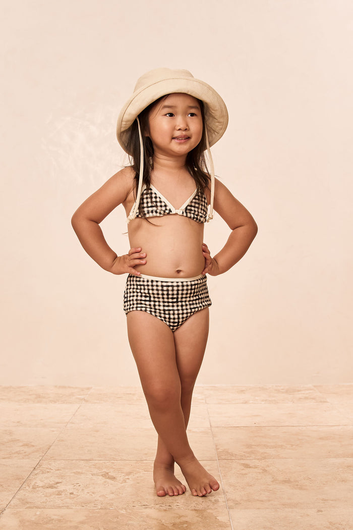 Front of Palma top and Seychelles bottom set in black gingham on model showing triangle top and high-rise bottoms on beige floor