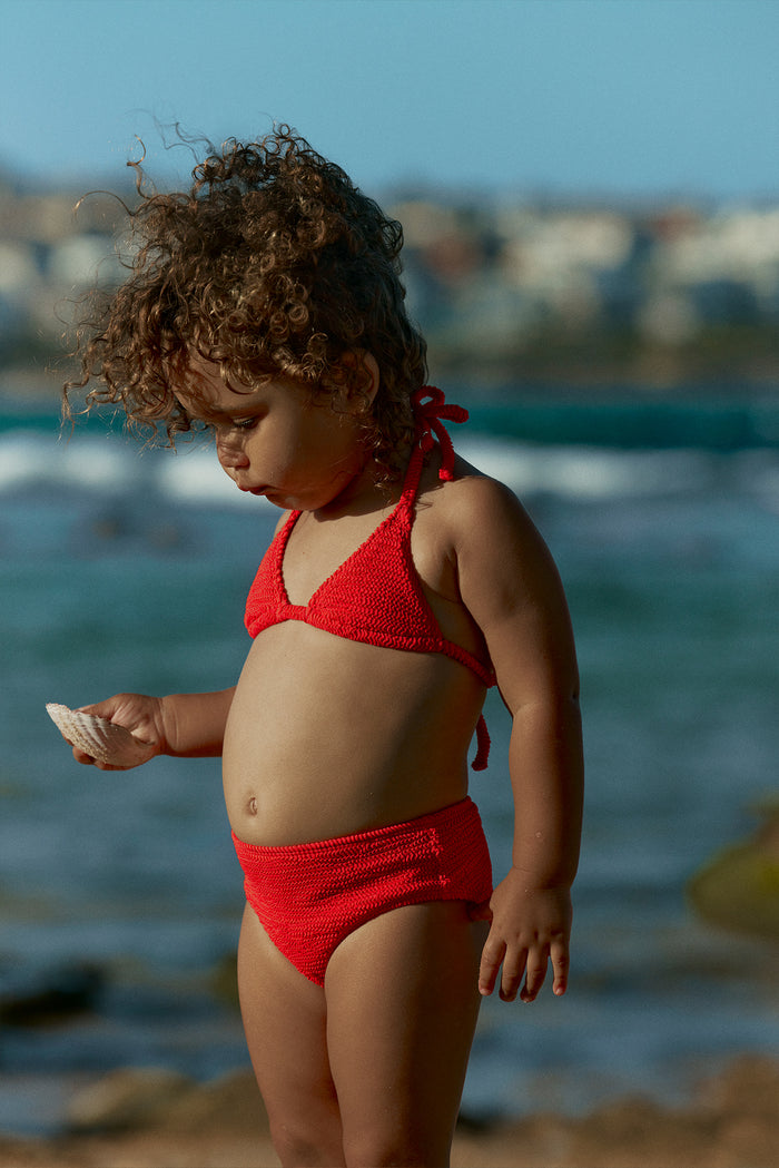Side view of Palma Top & Seychelles Bottom in Chili Pepper Crinkle, textured knit halter and high-waist bottoms on toddler at beach