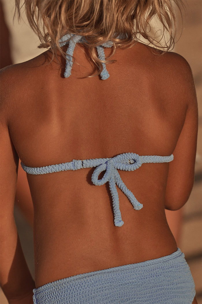 Back view of Palma Top & Seychelles Bottom Set - Pool Crinkle showcasing crinkle texture and tied halter straps on sunlit sandy beach