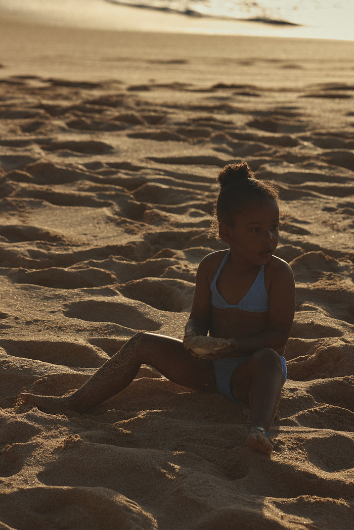 Toddler wearing Palma top and Seychelles bottom in Pool Crinkle, showing crinkle texture and halter top on sandy beach