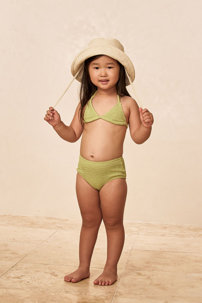 Front view of Panarea Mini Hat on child model showing natural canvas, chin tie, and short brim on neutral background