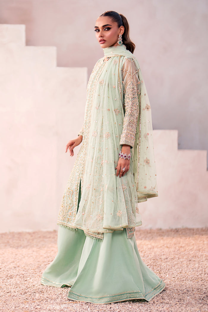 Side shot of Naqshi Parsa showcasing mid‑front slit with piping details, side‑seam embroidery, layered sharara flare and delicate dupatta drape.