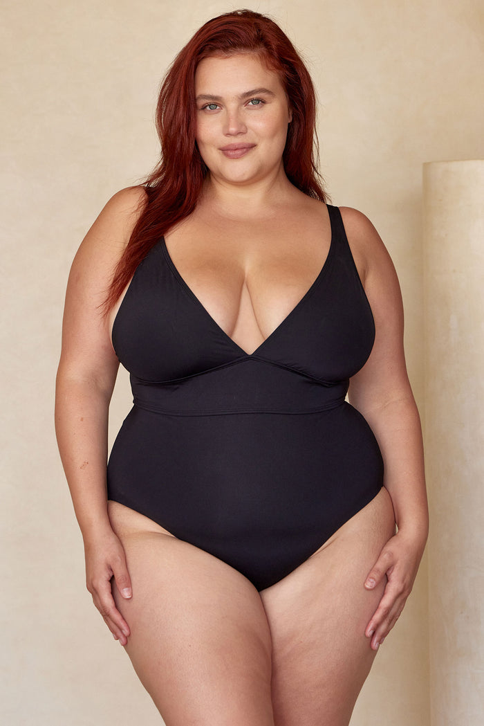 Front view of Portofino One Piece in black on a plus-size model, showing deep V neckline and supportive waist panel