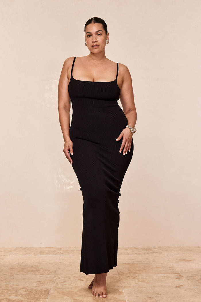 Front view of Provence Dress in black knit rib showing fitted ribbed silhouette, thin straps, and maxi length on beige tile