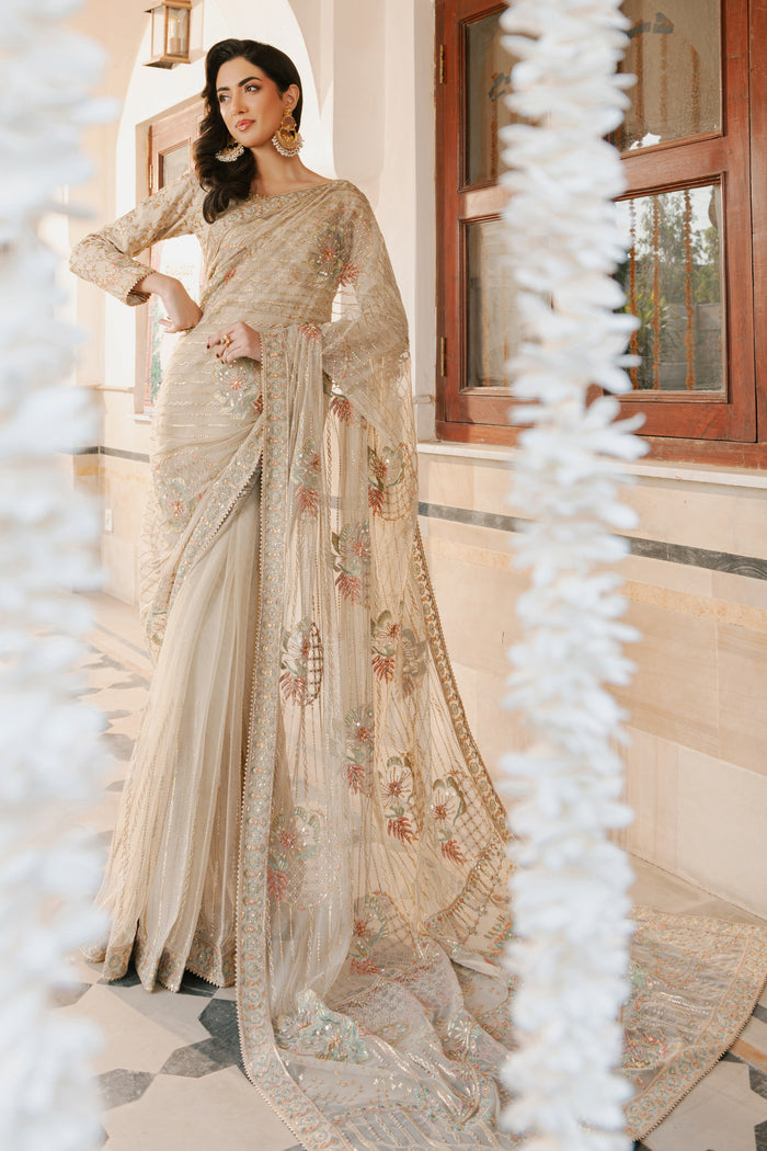 Model in full NAQSHI Ramish 3PC set: skin net saree, raw‑silk blouse with boat neck and fitted sleeves, floral‑embroidered pallu & raw‑silk petticoat