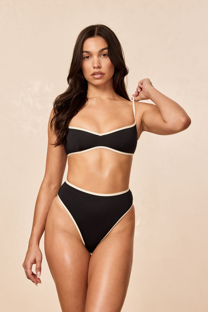 Front view of Ravello Bottom in Black/Ivory on model, high-waisted high-leg with cheeky coverage and ivory contrast trim