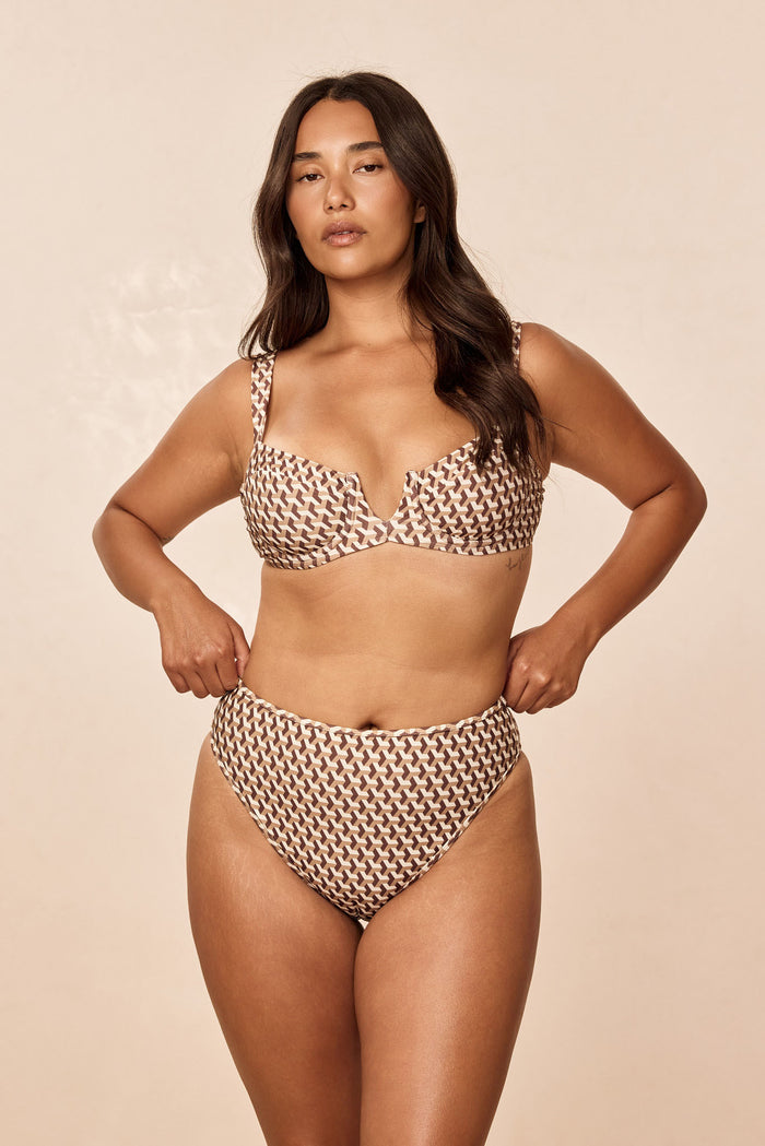 Front view of Ravello Bottom in Husk Geo on model showcasing high-waisted, high-leg cheeky coverage against beige background