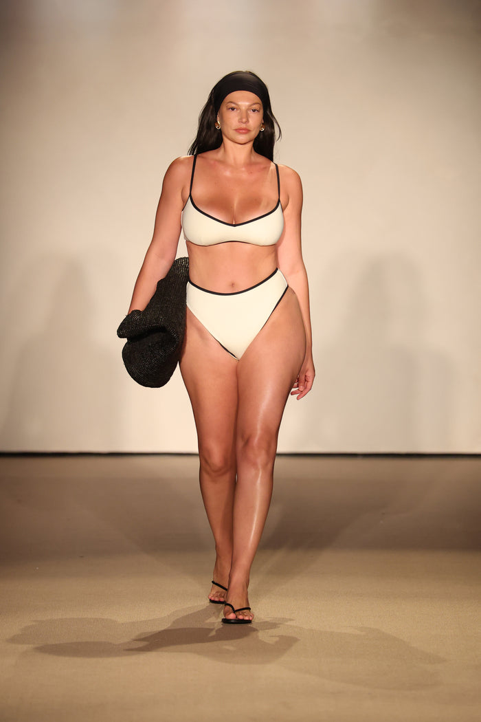 Front view of Ravello bottom in ivory with black trim on model showing high-waisted fit, high-cut leg and cheeky coverage on plain studio background
