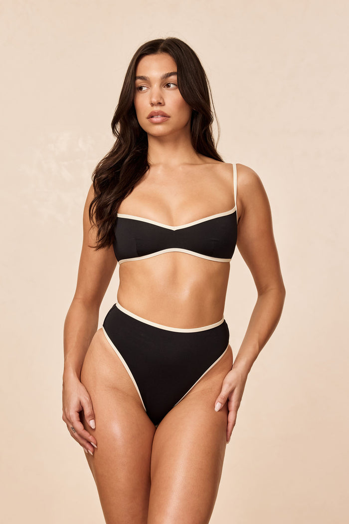 Front view of Ravello Top in black and ivory, balconette shape with contrast trim and thin straps on beige background