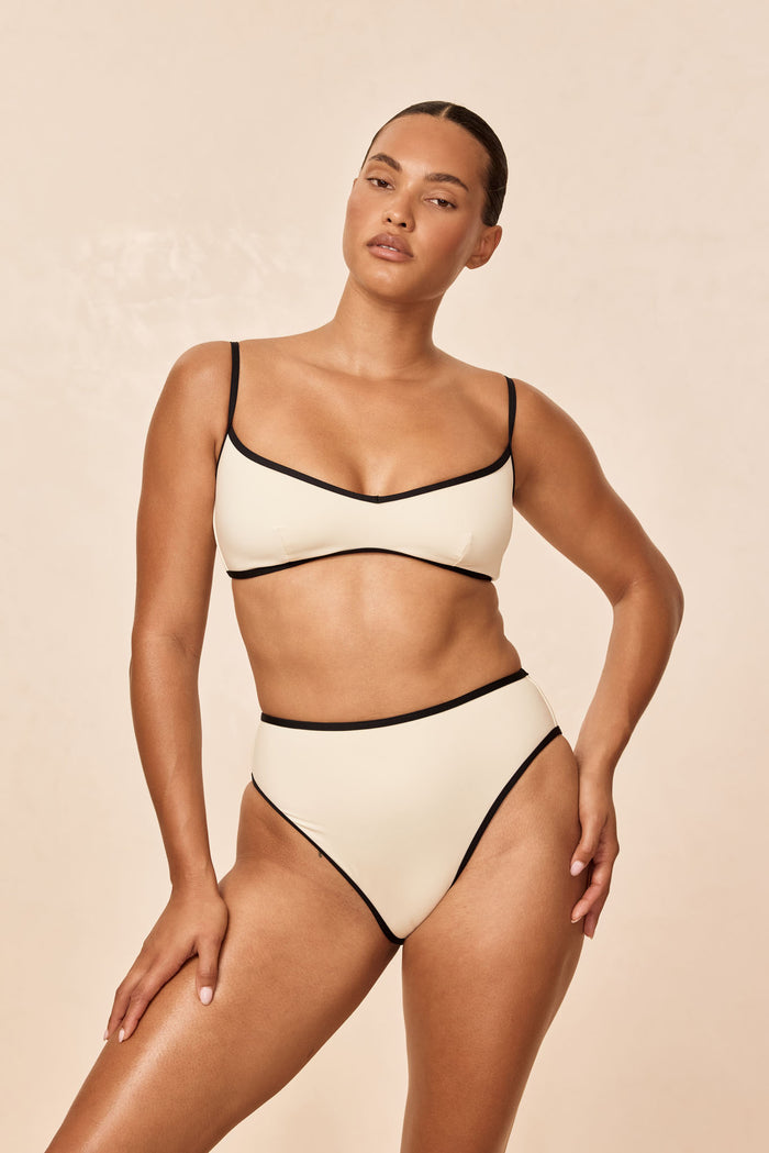 Front view of Ravello Top in ivory with black trim on model showing scoop neckline, thin straps, and smooth cups
