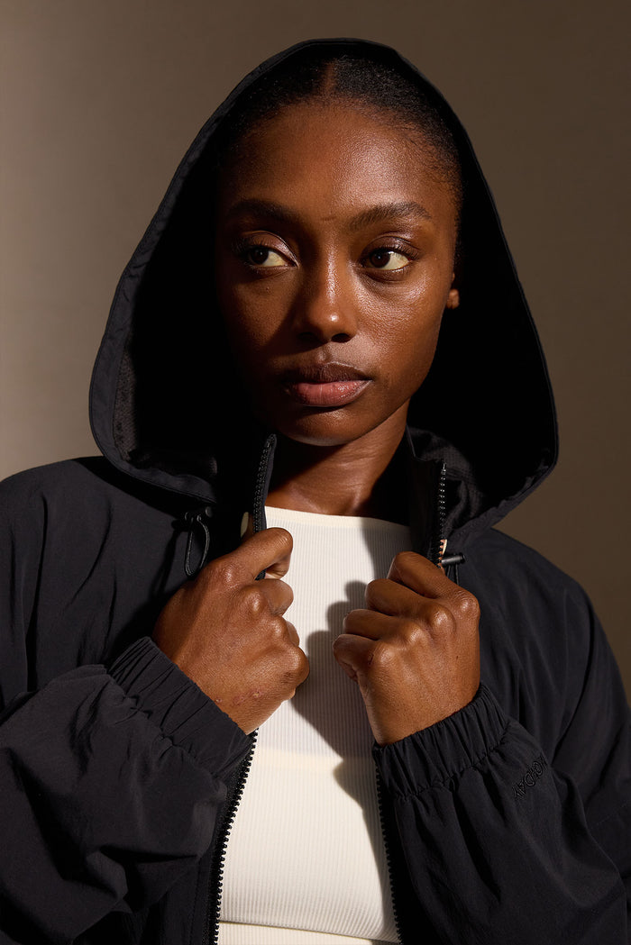 Close-up front view of Rexford Jacket in black on model showcasing hood, zip-front closure, and elastic cuffs against a neutral background