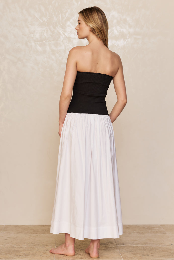 Back view of Rio Dress in white and black showing strapless smocked bodice and ankle-length gathered skirt on model