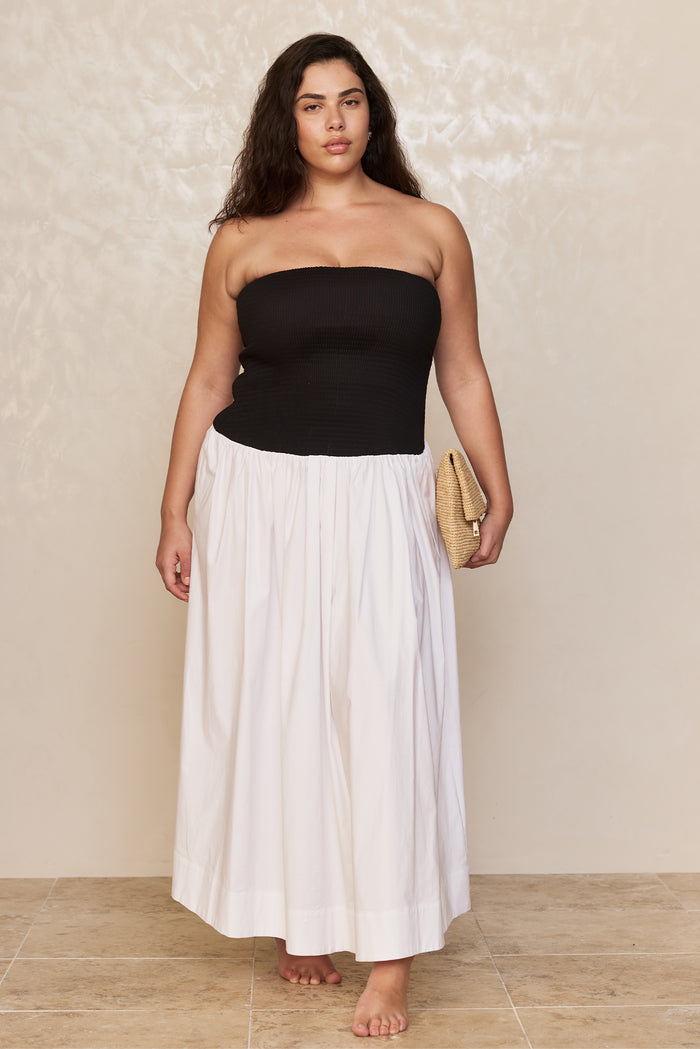 Front view of Rio Dress white/black on plus-size model, strapless smocked bodice and full white maxi skirt, beige background