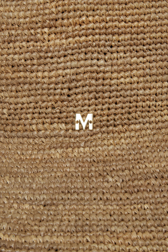 Close-up of Rio Hat in Husk showcasing woven raffia texture and gold M logo on the crown