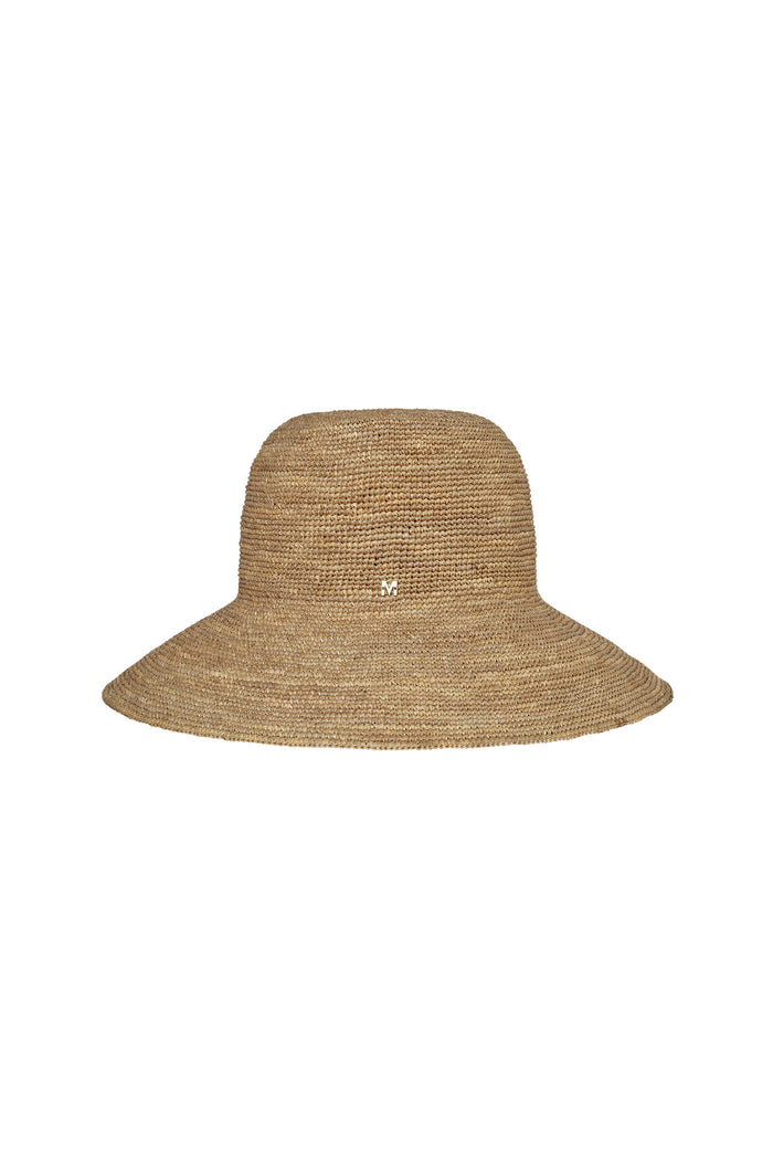 Front view of Rio Hat in natural husk showcasing packable raffia weave, 4.25-inch wide brim, and small gold M logo with white background