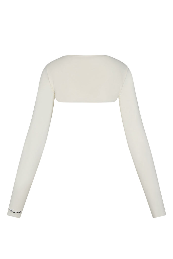 Ivory cropped shrug with long fitted sleeves; MONDAY printed near left cuff