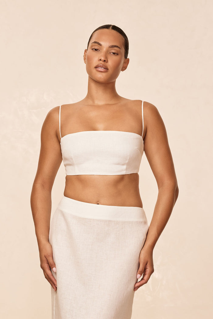 Front view of San Diego Top in White Linen on model, bandeau crop with thin shoulder straps and straight neckline against beige background