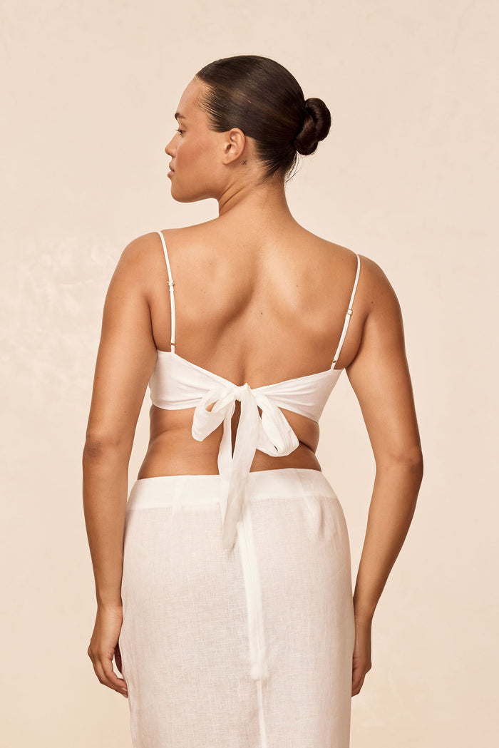 Back view of San Diego Top in white linen showing adjustable thin straps and a tie-back bow on a neutral beige background