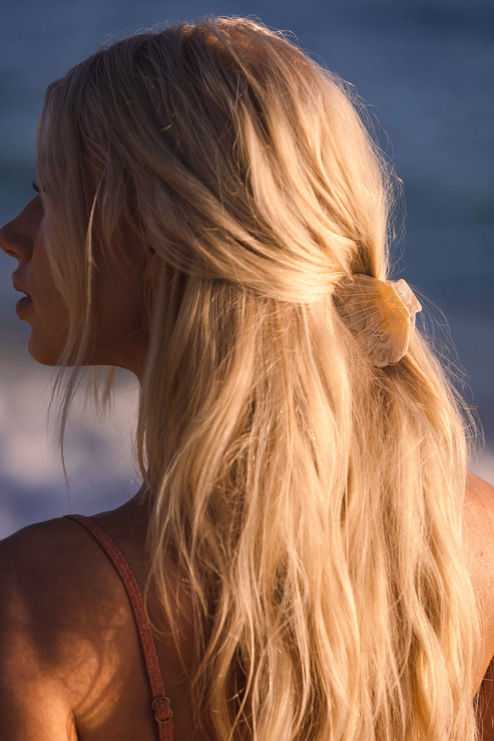 Back view of Sanibel Shell Hair Clip in Ivory Swirl showcasing shell shaped design in sunlit blonde hair at the beach