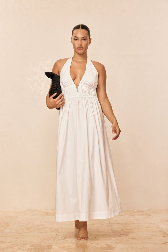 Front view of Santa Cruz dress in white with plunging halter V neckline and ankle-length skirt on beige background