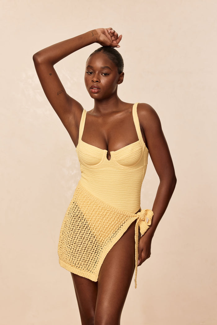 Three-quarter view of Santa Marta Sarong in Honey Petit Crochet with open-knit pattern and side-tie wrap on beige background