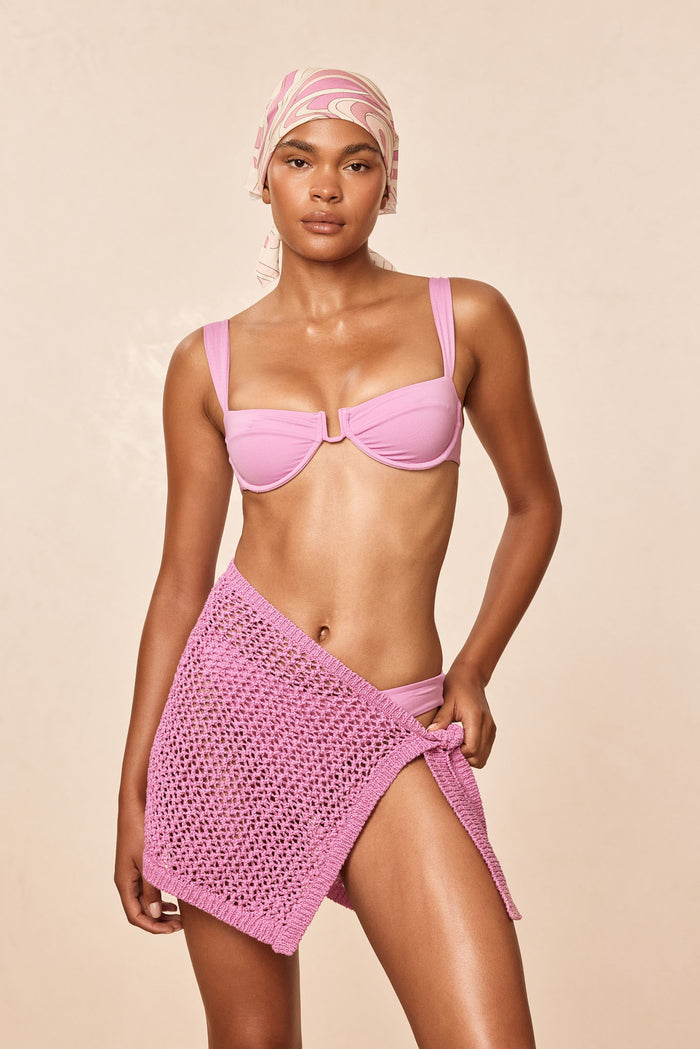 Front view of Santa Marta Sarong - Moonlight Petit Crochet showing adjustable wrap-style, sheer crochet knit tied at the hip on a model with beige background