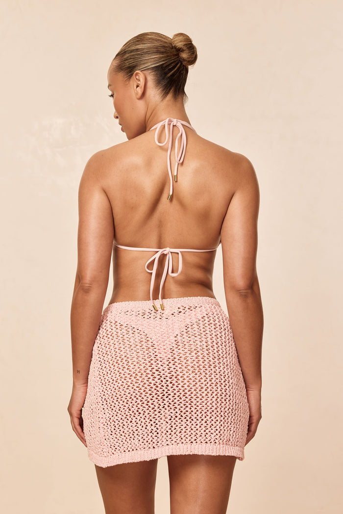 Back view of Santa Marta Sarong in powder pink petit crochet showing open crochet knit and mid-thigh length on model