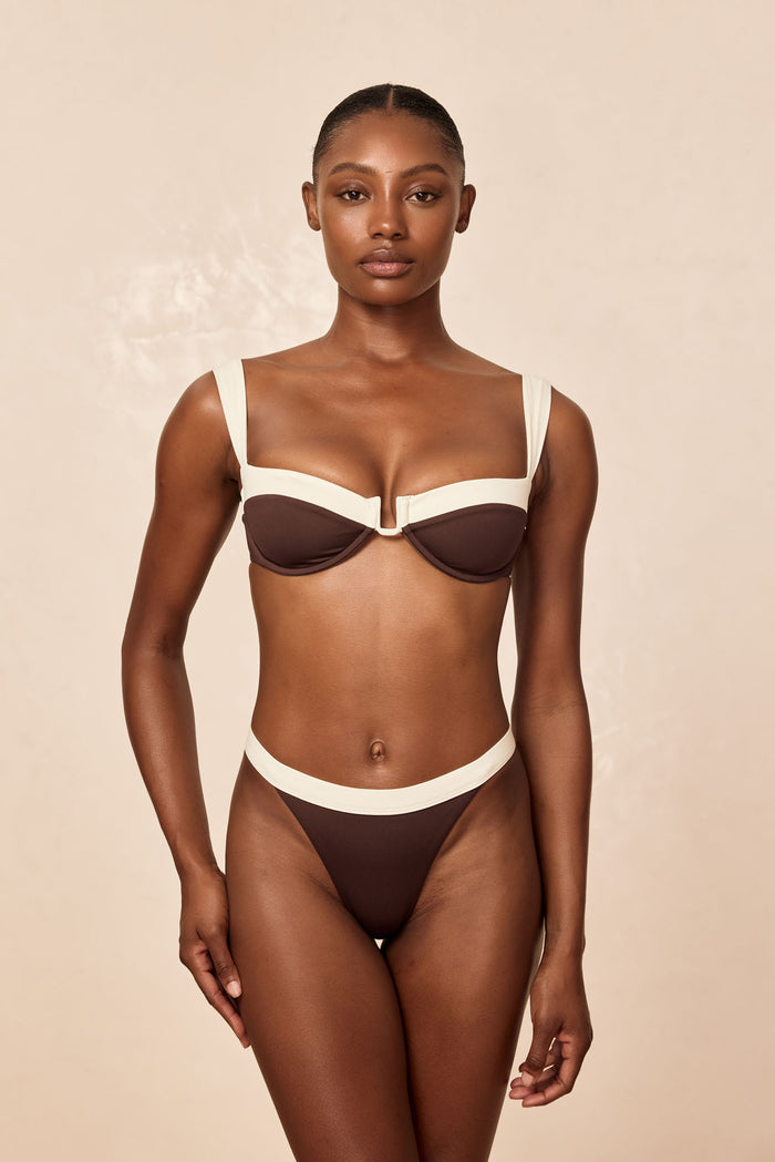 Front view of Cala Roja Top in espresso and ivory showing underwire balconette cups and wide ivory straps on a beige background