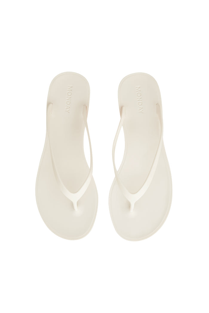 Top-down view of Sardinia Sandal in ivory showing jelly thong straps and debossed MONDAY logo on white background