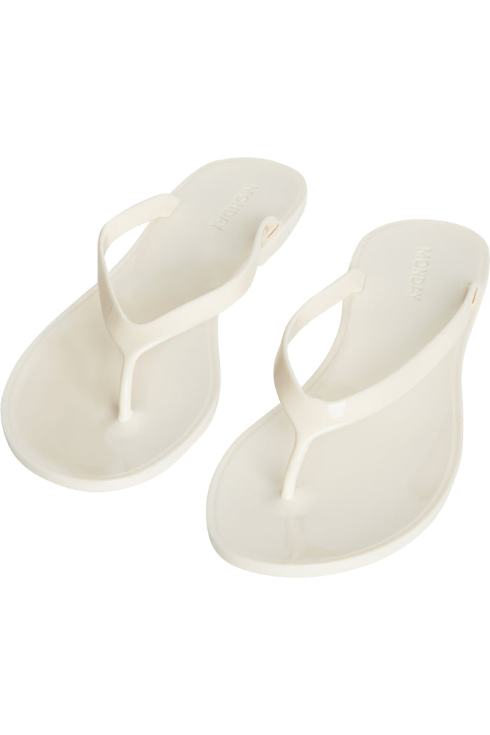Top view of Sardinia Sandal in ivory showcasing glossy jelly thong straps and debossed MONDAY logo on white background