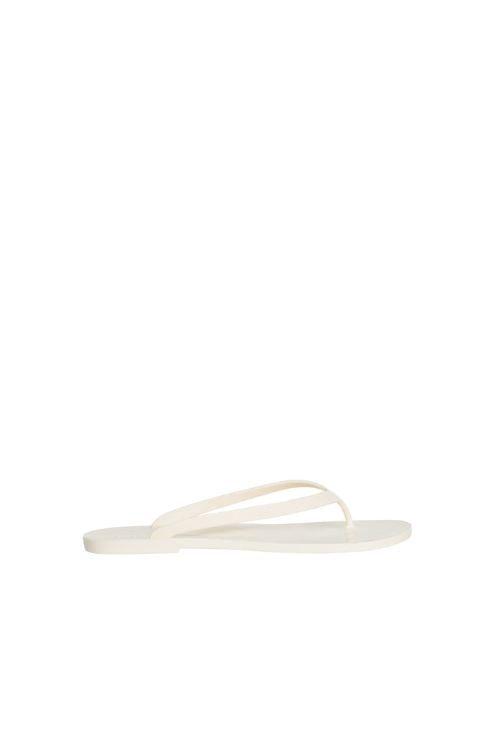 Side view of Sardinia Sandal in ivory showing thin jelly toe-post straps and flat sole on white background