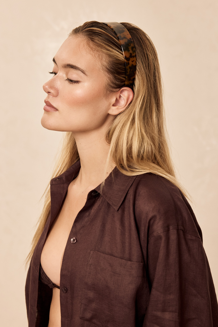 Side profile of Sayulita Headband in tortoise on model showcasing marbled acetate pattern and wide band against beige background
