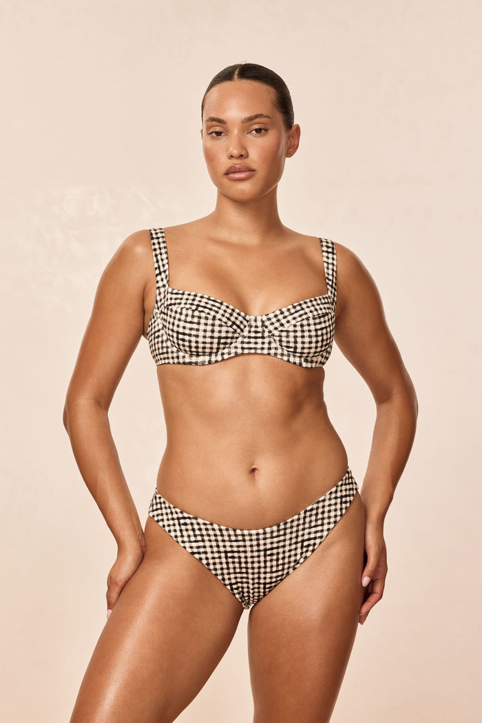 Front view of Seychelles bottom in black gingham on model showing mid-rise, high-cut leg against beige background