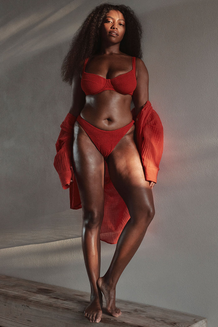 Front view of Seychelles modest-coverage bottom in Chili Pepper Crinkle on model, showing textured high-rise fit against neutral studio backdrop