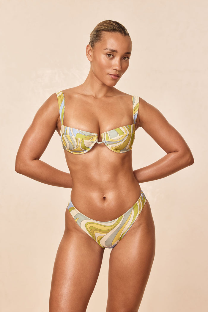 Front view of Seychelles bottom in Costa Rei Apple print on model showing high-cut, mid-rise fit on beige background