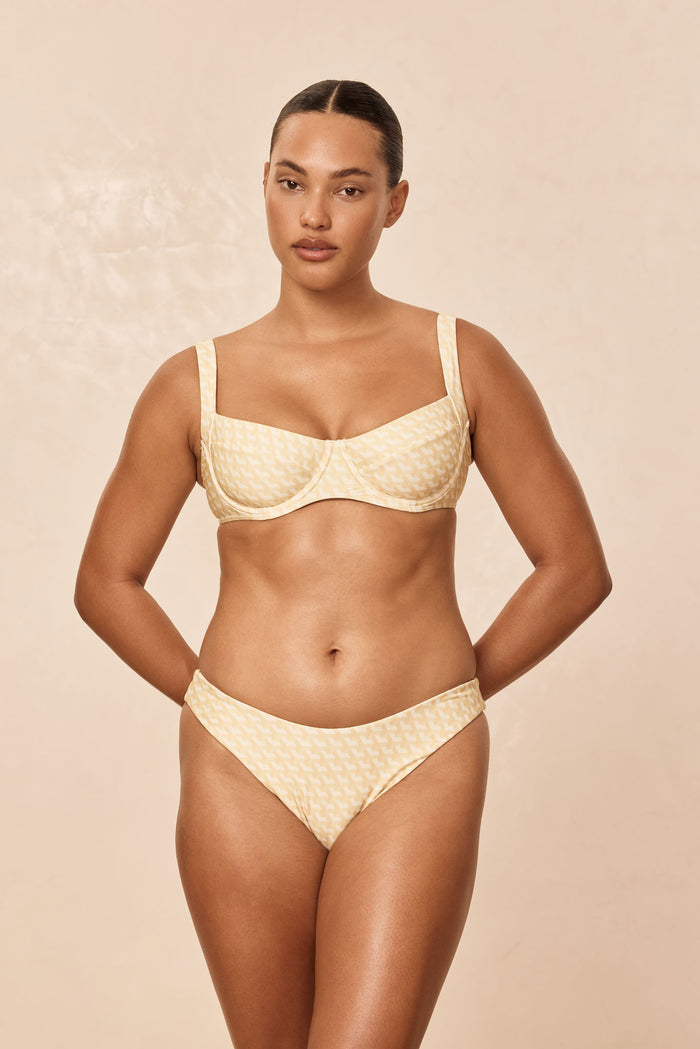 Front view of Seychelles swim bottoms in ivory geo print showing modest coverage on model against a beige studio background