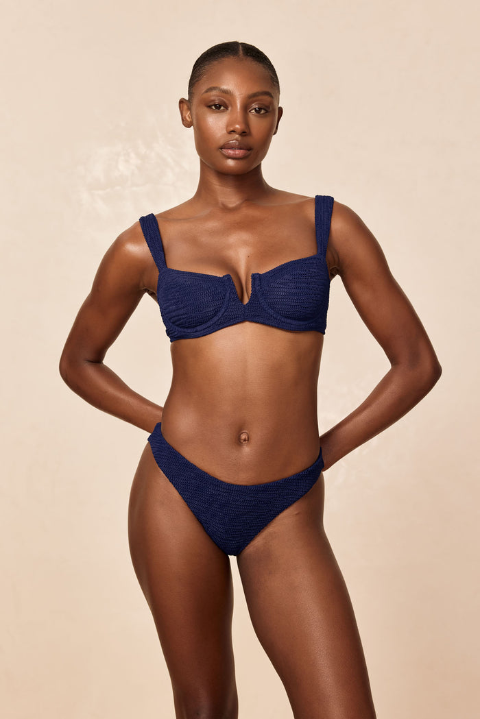 Front view of Seychelles bottom in Midnight Crinkle on model showing crinkle texture and modest coverage against beige background