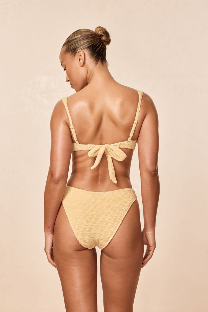 Back view of Seychelles Bottom Raffia Crinkle showcasing cheeky high-rise cut and textured crinkle fabric with beige studio background