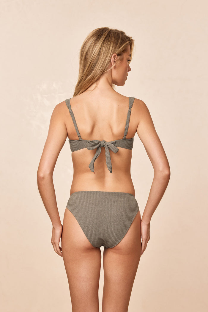 Back view of Seychelles Bottom in Steel Lurex Rib showing modest coverage and ribbed texture on model on beige background