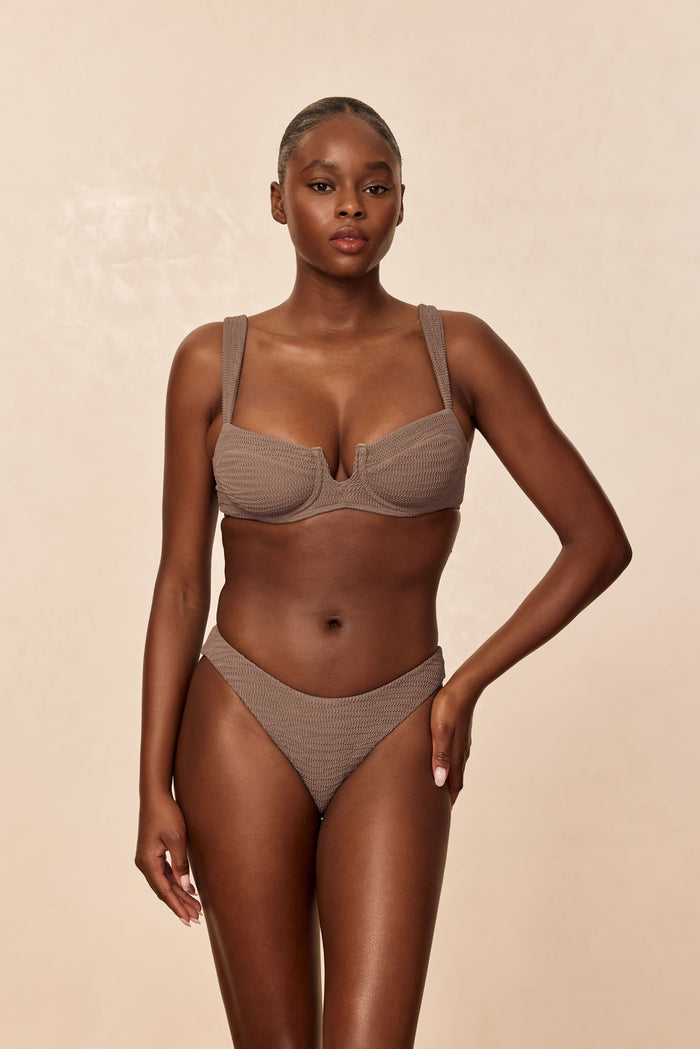 Front view of Seychelles Bottom in Stone Crinkle, textured fabric and high-cut leg on model against beige background