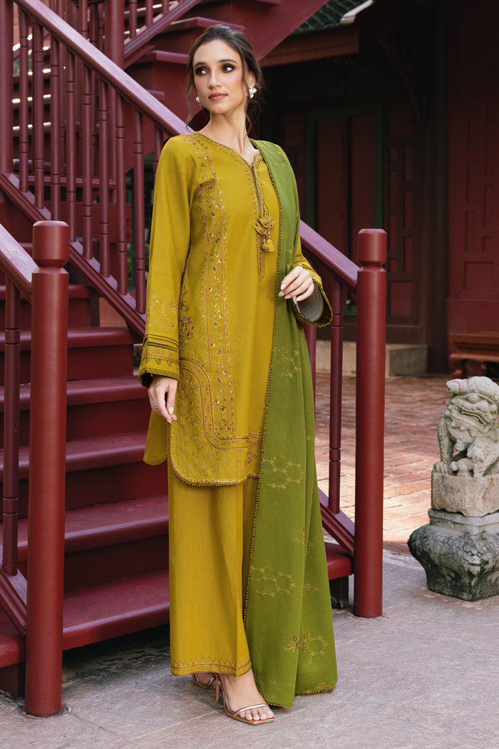 Woman in a green and yellow traditional outfit standing in front of a red staircase.