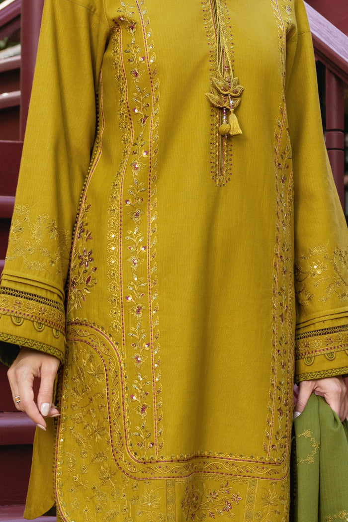 Mustard yellow embroidered traditional outfit with green pants, held by a hand.