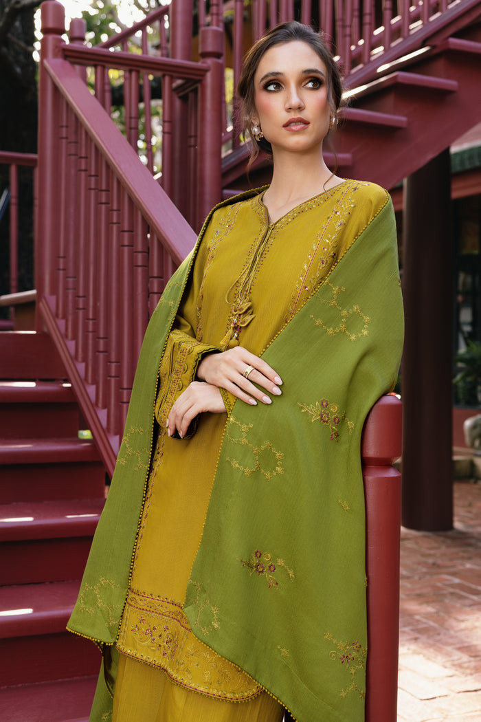 Woman wearing a green and yellow traditional outfit standing in front of red steps.