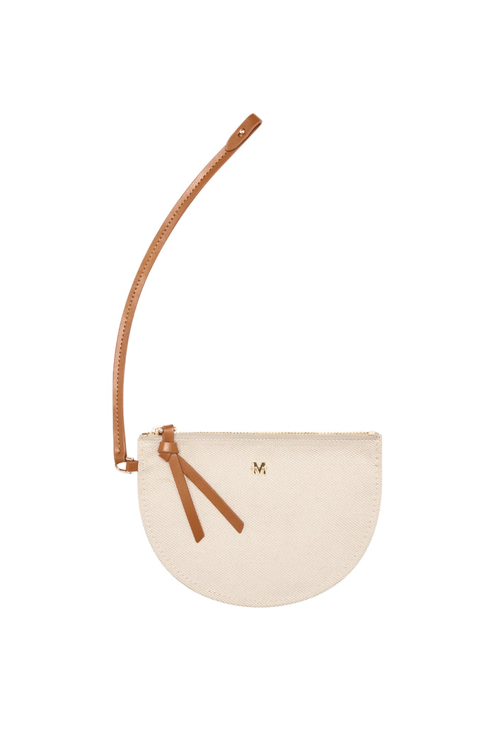 Partial top view of Shell Beach Bag in Natural showing tan shoulder strap and matching mini pouch with gold M logo on white