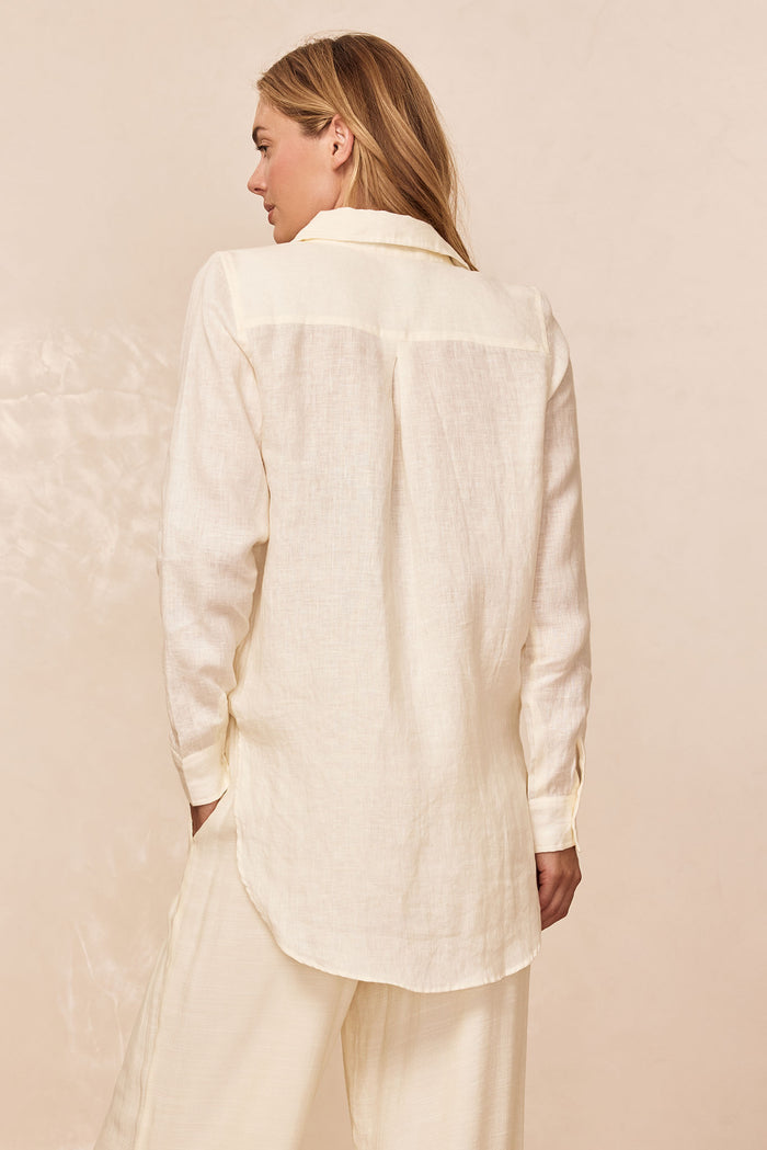 Model seen from back wearing cream linen long-sleeve shirt and matching wide-leg pants