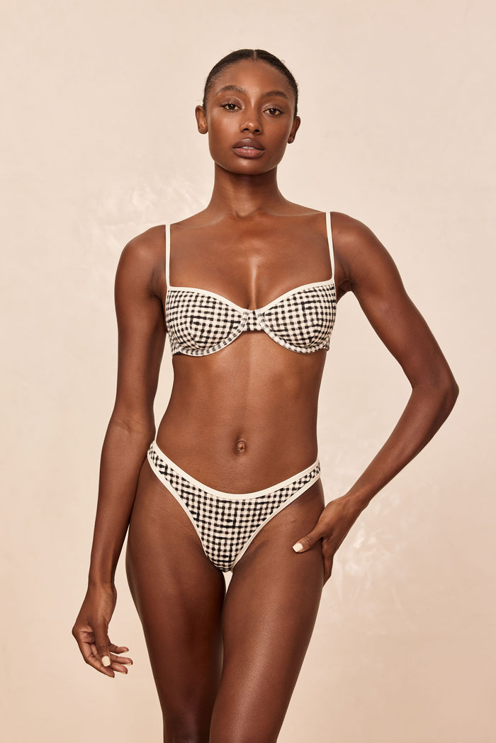 Front view of Somerset Bottom in Black Gingham showcasing mid-rise high-cut leg, cheeky coverage, and cream contrast binding on beige background