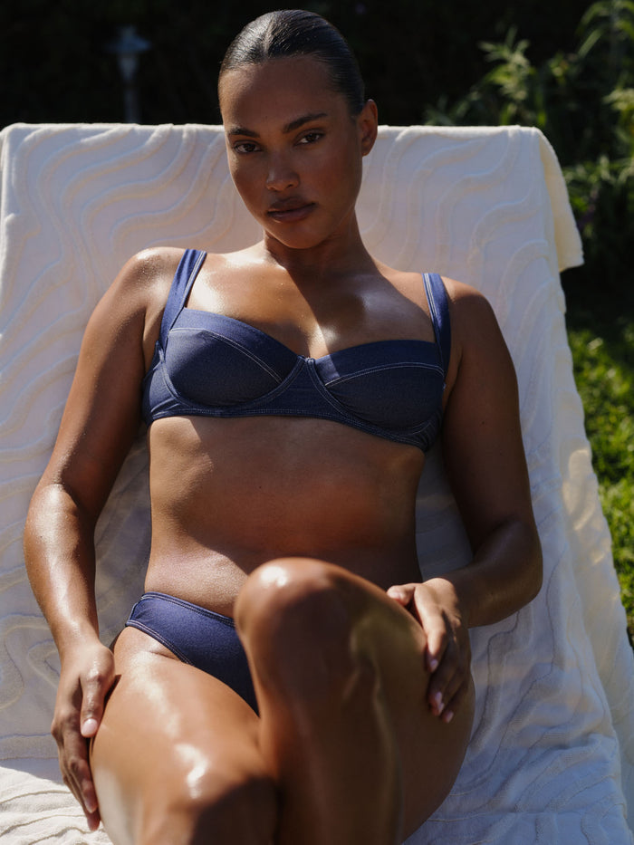 Front view of Sorrento Top in Blue Denim on a reclining model, showing underwire cups, seam detail, and matching bottoms