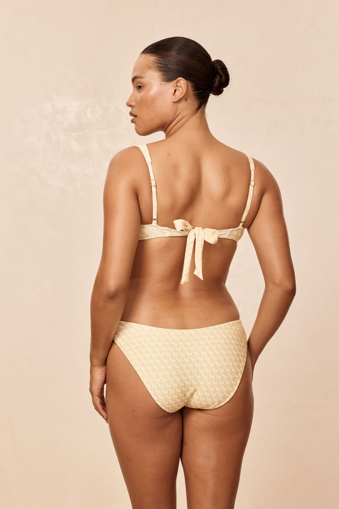 Rear view of Sorrento Top in Ivory Geo on model, showing back tie and adjustable straps against a beige studio background